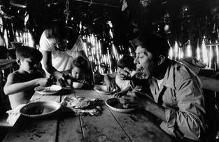 Las tortillas calientes se mantienen tibias en un paño en el centro de la mesa. Pedazos de tortilla se usan como cucharas para tomar el caldo de frijoles negros. Chichimilá, 1976.