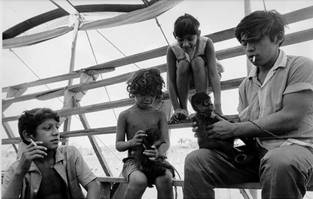 Marta Elena, la hija menor de la familia, muestra a Robert Everton el circo de los monos, mientras dos empleados le enseñan frases interesantes en maya y español. Circo Mágico Modelo. Limones, 1971.